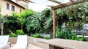 An outdoor patio area with a stone-tiled table and white lounge chairs. - The Secret Garden - Italian Homing (Padenghe sul Garda)