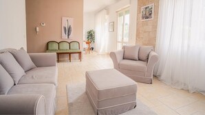 A living room with two sofas, a coffee table, a dining area with a table and chairs, and a large window with curtains. - The Secret Garden - Italian Homing (Padenghe sul Garda)