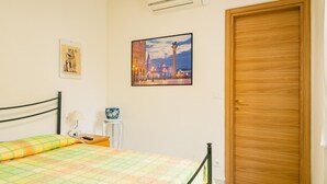 A bedroom with a bed, a nightstand, a lamp, a picture frame, and a wooden door. - La Casa di Nonna Agnese - Italian Homing (Padenghe sul Garda)