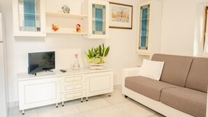 A living room with a white TV stand, a brown sofa, and a small plant. - La Casa di Nonna Agnese - Italian Homing (Padenghe sul Garda)