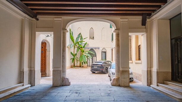 Un cortile coperto con pavimento in pietra, colonne e un'auto parcheggiata.