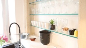 Una cucina con ripiano in vetro che contiene tazze e una piccola pianta in vaso.
