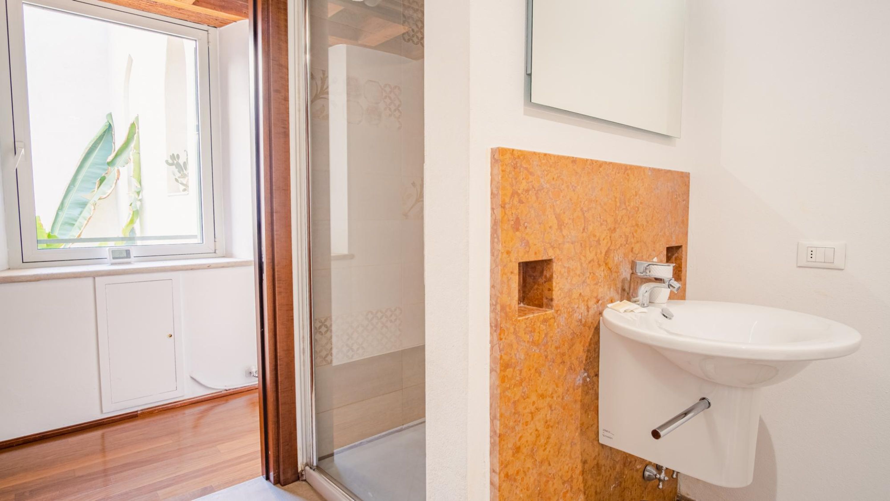 Ein Badezimmer mit einem weißen Waschbecken, einem Spiegel und einer Dusche.