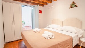 Una camera da letto con un letto, due asciugamani arrotolati, un armadio e vista sull'esterno.