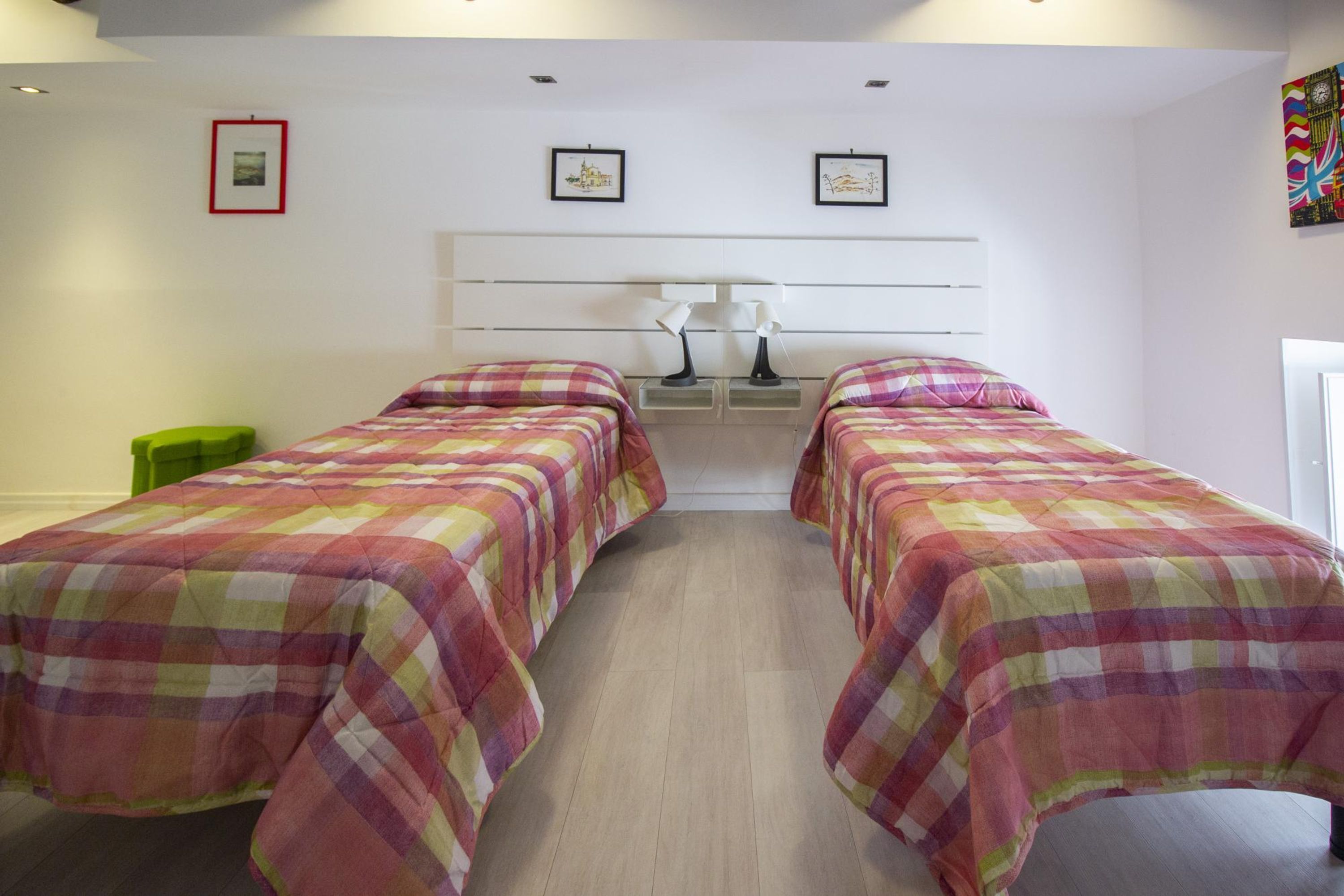 A bedroom with two beds, a nightstand with a lamp, and a green chair.
