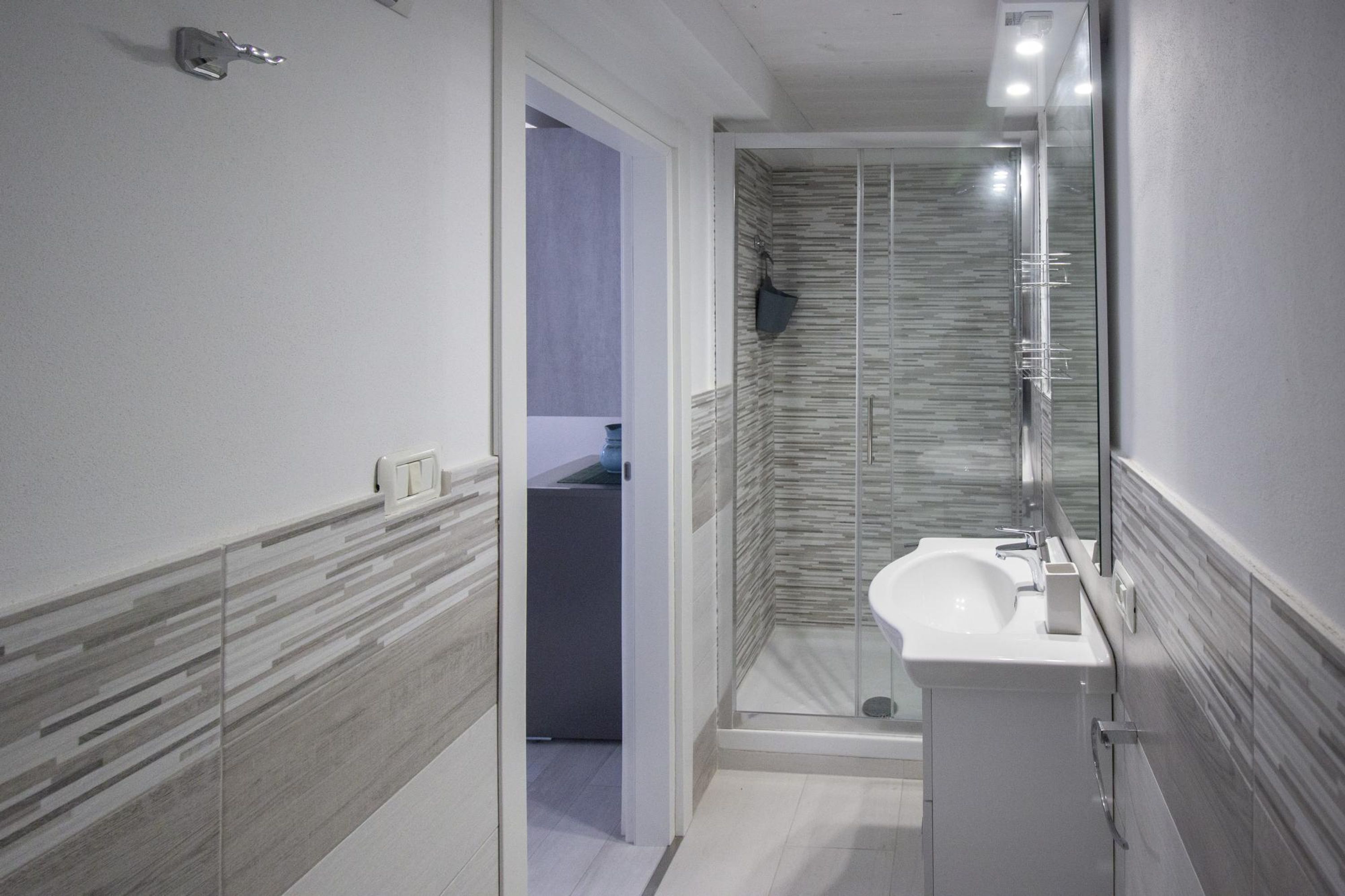 Une petite salle de bain avec une douche en verre, un lavabo blanc et un miroir.