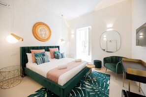 Une chambre à coucher moderne avec un lit recouvert d’un tissu vert, un miroir rond et un bureau avec une chaise.