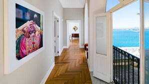 A hallway with a wooden floor leading to a balcony with a sea view. - Aretusa Exclusive Sea View (Syracuse)