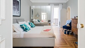 A bedroom with a large bed, a dresser, a chair, and a mirror. - Aretusa Exclusive Sea View (Syracuse)