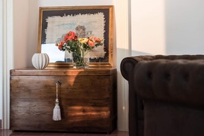 A wooden nightstand with a vase of flowers and a framed picture.