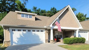A two-story house with a garage, a small porch, and an American flag.