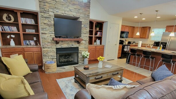 A living room with a stone fireplace, leather sofas, and a flat-screen TV.