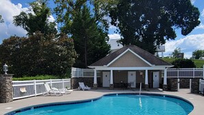 A swimming pool with a stone wall and a covered seating area.