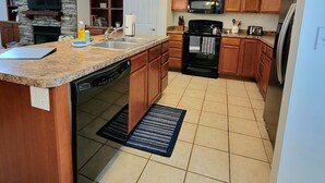 A modern kitchen with granite countertops, wooden cabinets, a built-in oven, microwave, and refrigerator.