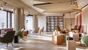 Een moderne loungehoek met houten vloeren, strakke meubels en een grote boekenkast.