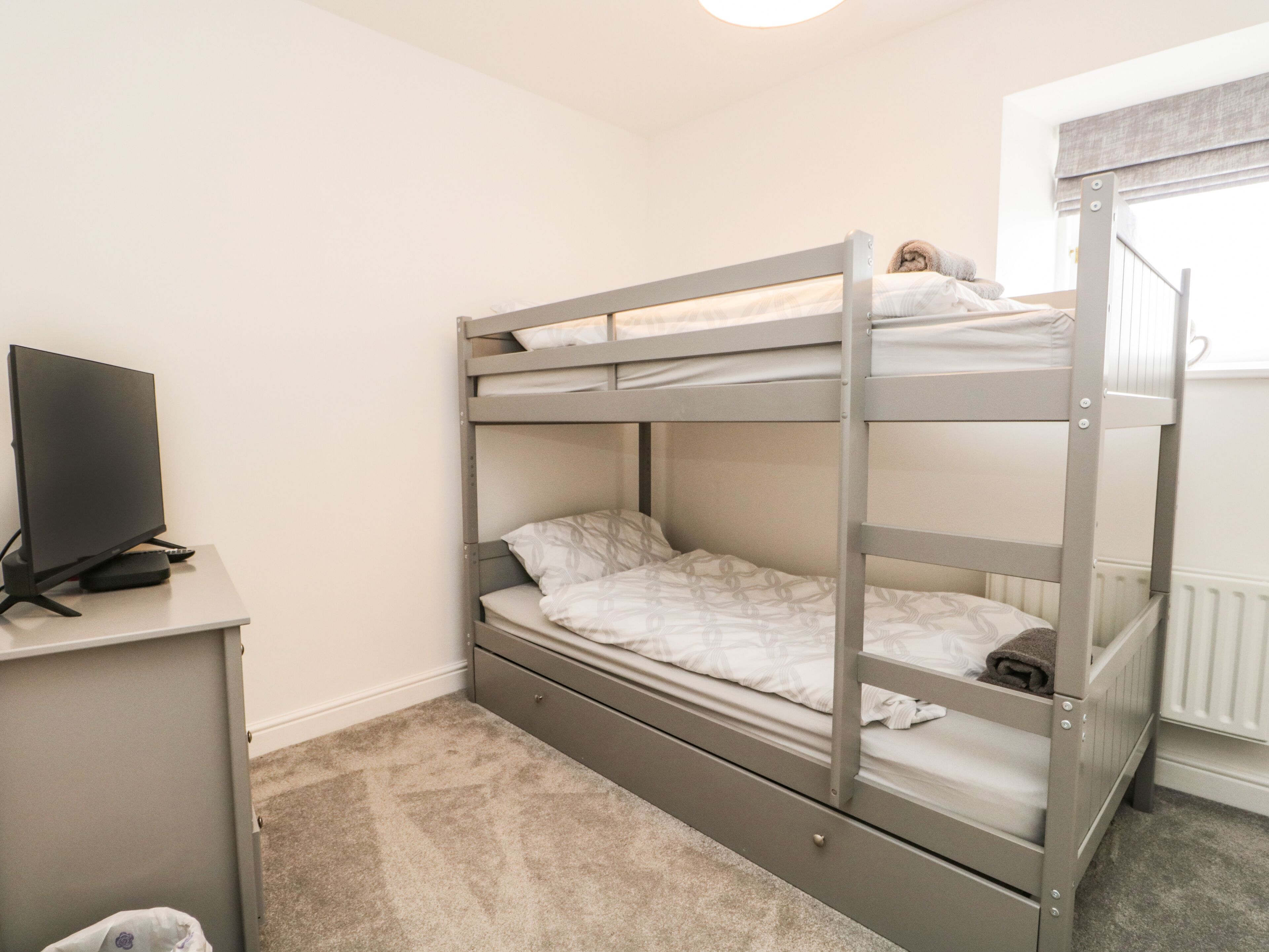 A bunk bed room with a TV on a desk.