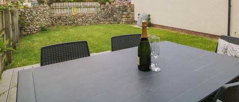 Un patio al aire libre con una mesa preparada para dos personas, una botella de champán y una copa.
