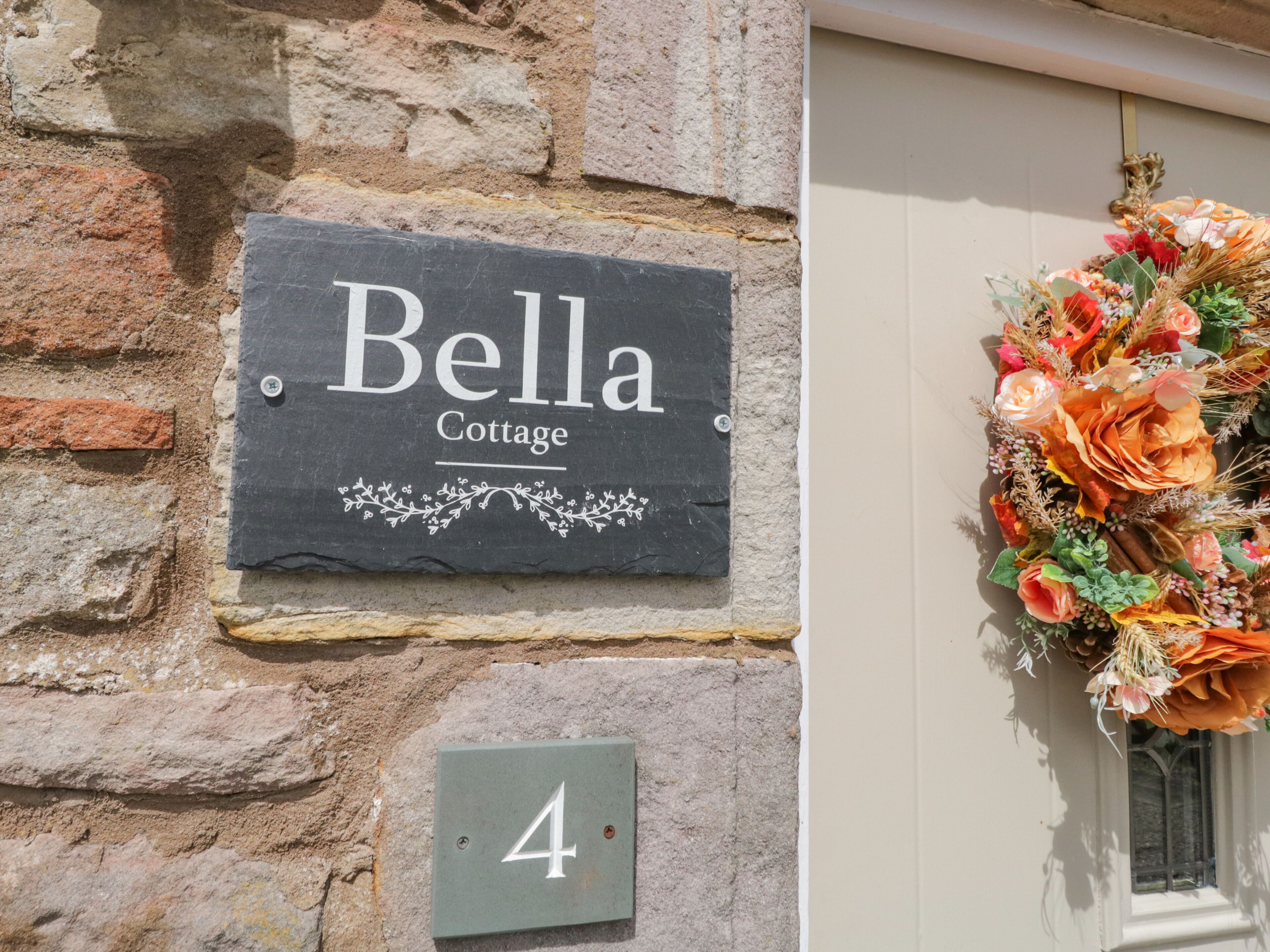 A stone wall with a sign reading "Bella Cottage" and a number "4" below it.