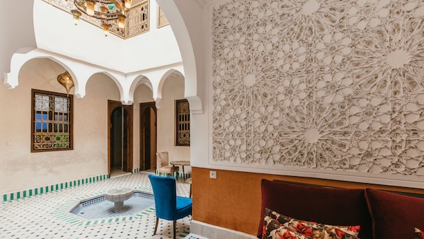 A spacious interior with a high ceiling, a fountain, and a patterned wall. - Charming, quiet and comfortable Riad (Marrakech)