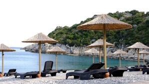 Een strandlounge met rieten parasols en ligstoelen.
