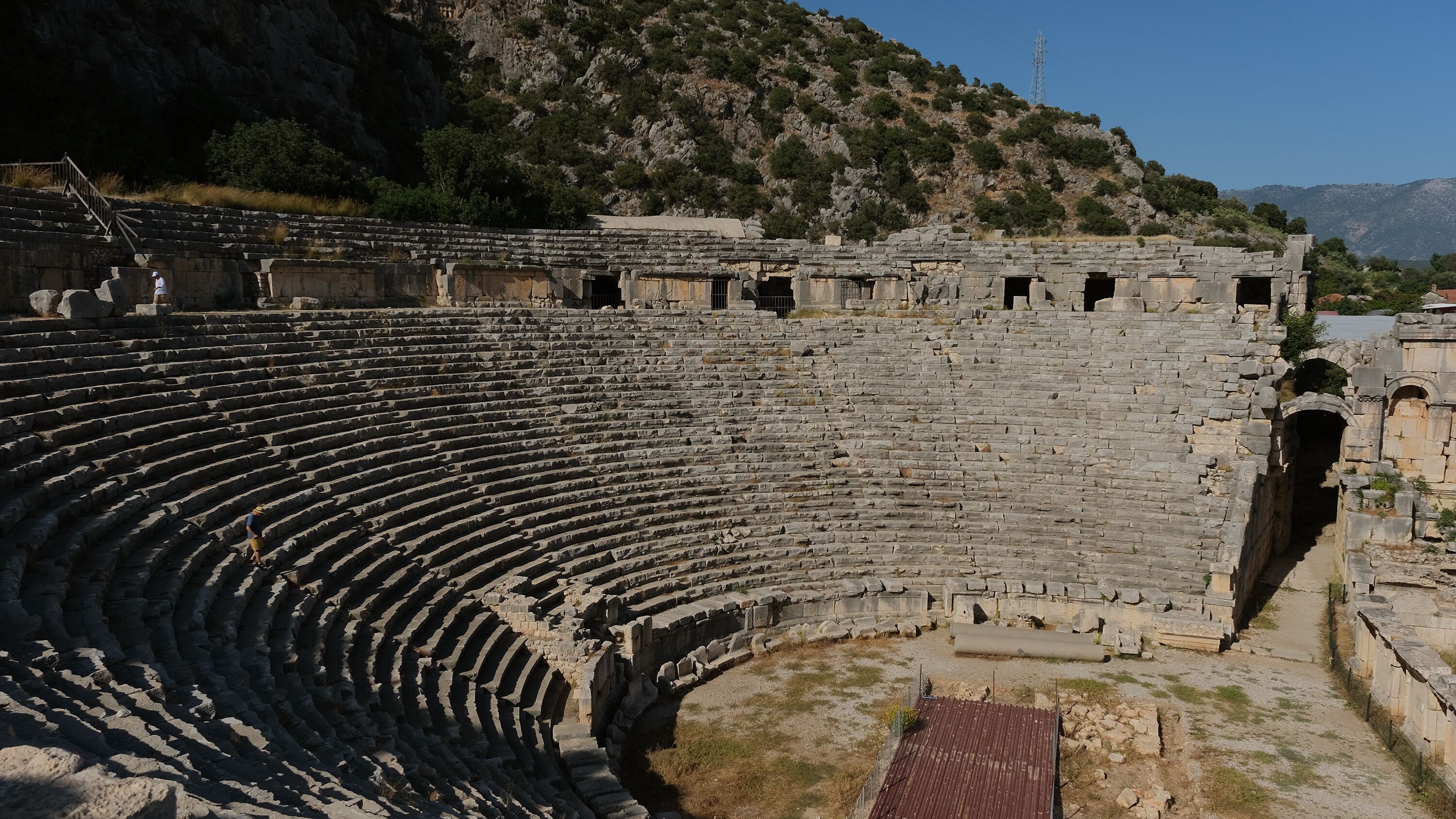 Un antiguo anfiteatro de piedra con gradas escalonadas y un espacio central para el escenario.