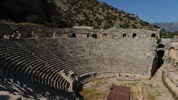 Un antiguo anfiteatro de piedra con gradas escalonadas y un espacio central para el escenario.