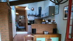 Een houten eettafel met stoelen, een bakstenen muur en een keuken met kasten en een fornuis.