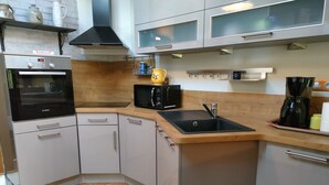 Een kleine keuken met een Bosch oven, een magnetron, een spoelbak en een koffiezetapparaat.