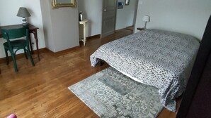 Een slaapkamer met een bed, een bureau, een stoel en een spiegel.