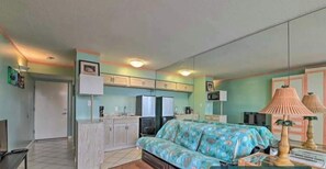 A compact room with a bed, kitchenette, and a small dining area.