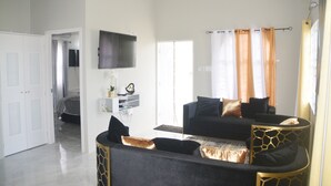 A modern living room with a black sofa, a coffee table, and a TV mounted on the wall.