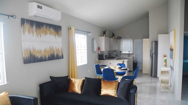 A modern living room with a black sofa, blue chairs, and a dining area with a small table.