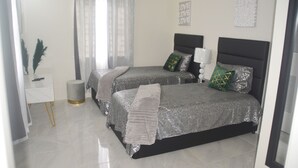 A bedroom with two beds, a bedside table, a lamp, and a mirror.