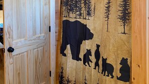 Un interior de madera con una puerta y una cortina que presenta siluetas de animales y bosques.