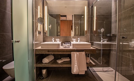 A modern bathroom with two sinks, a large mirror, and a glass shower enclosure.. Hotel Giralda Center