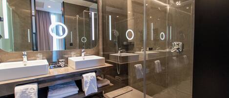 A modern bathroom with two sinks, a large mirror, and a glass-enclosed shower area.