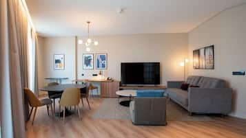 Uma sala de estar moderna com área de jantar, televisão de tela plana e sofá.