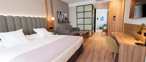 A modern hotel room with a large bed, a desk, a chair, and a television.