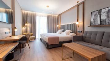 Habitación de hotel moderna con cama, sofá, escritorio y sillas.
