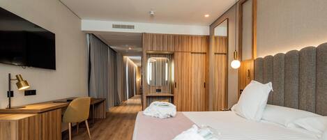 Una habitación de hotel con cama, escritorio, silla, televisor y espejo.