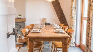 A dining room with a long wooden table set for a meal, surrounded by wooden chairs. - Byre Cottage, a Lake District cottage on a working farm (Broughton-in-Furness)