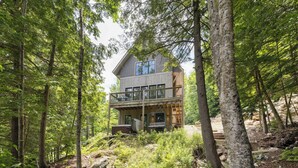 A two-story cabin surrounded by dense forest. - Mountainside 3-BR Ski-In/Out Okemo Chalet (Ludlow)