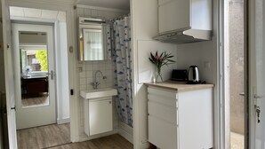 Une cuisine compacte comprenant un évier, un petit meuble de rangement, un grille-pain et un vase avec des fleurs.