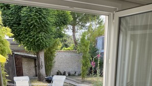 Une pièce donnant sur un jardin, une table avec un set de table jaune, une chaise et un ensemble de vaisselle.