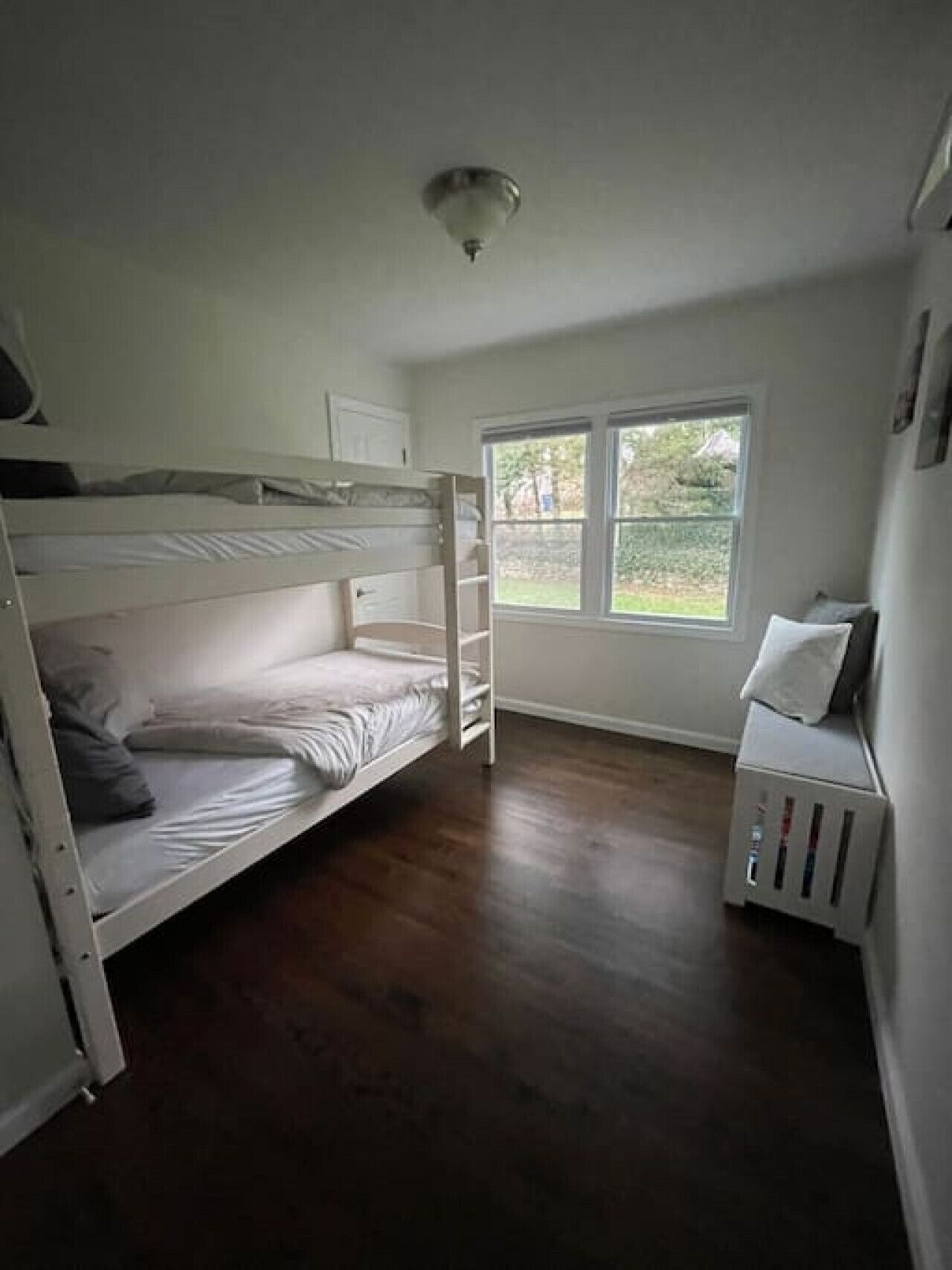 Ein Zimmer mit Etagenbett, einem Fenster mit Blick auf Grünflächen und einer Heizung.