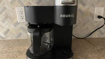 Une machine à café Keurig posée sur un comptoir de cuisine, avec un pare-feu décoré d’un motif en chevrons.