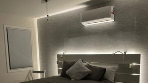 A modern bedroom with a bed, a ceiling fan, and built-in lighting.