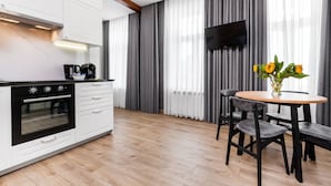 Une cuisine moderne avec des meubles blancs, une cuisinière noire et une table à manger en bois, accompagnée de chaises.