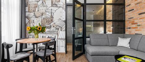 A modern living room with a dining area, a grey sofa, and a table with a book.