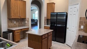 A kitchen with granite countertops, wooden cabinets, a double-door refrigerator, and a built-in island. - Backyard Sanctuary with 4 Bedrooms House (Plano)